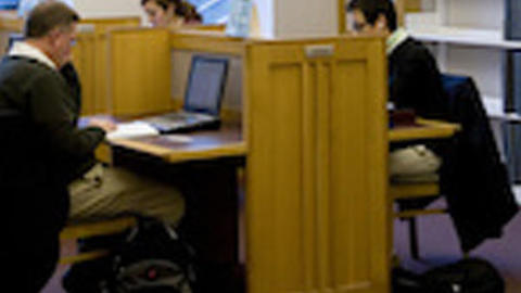 People studying at a shared desk in the library