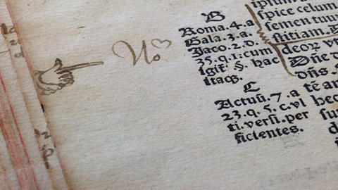 Writing and a pointing finger drawn in the margin of a rare book.