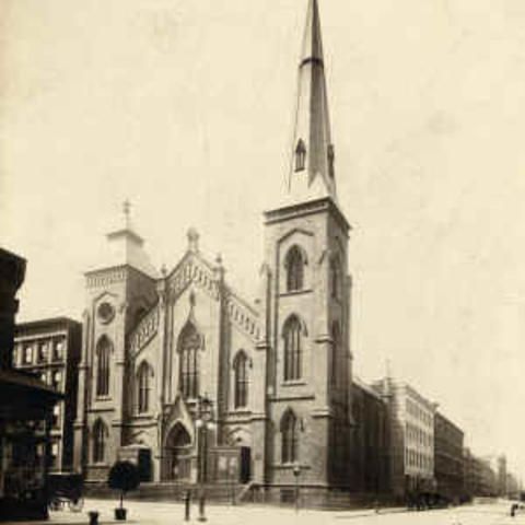 Historic photograph of a Gothic church with a tall corner tower and steeple